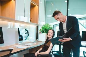 Serious and focused business man and entrepreneur working and reading file with female secretary and employee in meeting room in modern office photo