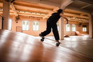 mujer patinadora jugando patineta en el gimnasio deportivo, la joven asiática es feliz y divertida con el estilo de vida de patinaje en la ciudad, la moda femenina hipster adolescente foto