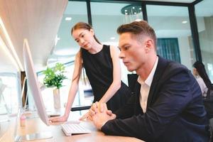 Young female business person in conversation with male manager or colleague or boss while giving presentation on project research work using laptop in conference room in modern office photo