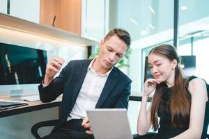 Serious and focused business man and entrepreneur working and reading file with female secretary and employee in meeting room in modern office photo