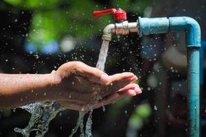 Water concept in everyday life. Hands supporting the water flowing from the faucet. water splashing from the tap photo