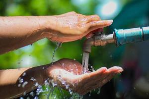 Water concept in everyday life. Hands supporting the water flowing from the faucet. water splashing from the tap photo