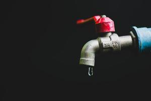 concepto de crisis de escasez de agua dulce debido a cambios ambientales. grifo de agua sin agua corriente sobre un fondo negro hay un espacio de copia. foto