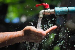 Water concept in everyday life. Hands supporting the water flowing from the faucet. water splashing from the tap photo