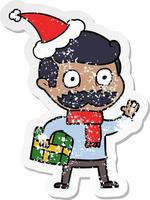 distressed sticker cartoon of a man with mustache and christmas present wearing santa hat vector