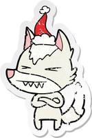 angry wolf distressed sticker cartoon of a wearing santa hat vector