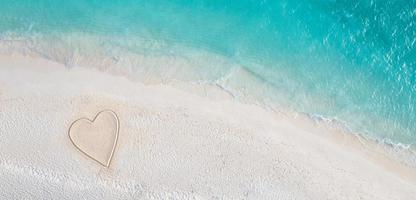 dibujo perfecto de forma de corazón en arena suave fondo hermoso paisaje marino. día de san valentín romántico o escena de playa de amor, vista aérea superior. romance, luna de miel en vacaciones, viajes de verano. naturaleza idílica foto