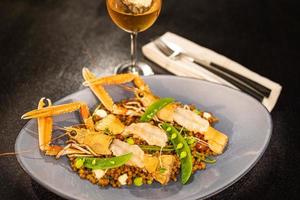 gambas hervidas con guisantes y salsa en un plato elegante con vino rosado. aperitivo de cena gourmet de lujo foto