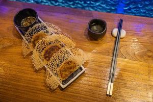 Fried dumplings Gyoza in a frying pan, soy sauce, and chopsticks on a brown wooden background, top view photo