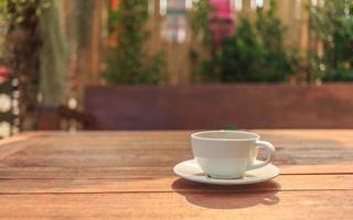 cup of coffee on wooden table in morning sun photo