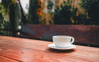 cup of coffee on wooden table in morning sun photo