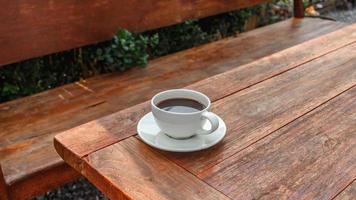 cup of coffee on wooden table in morning sun photo