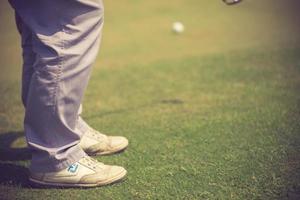 Golf player at the putting green hitting ball into a hole.Vintage color photo