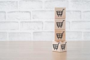 Shopping online concept, Shopping cart icons on cubes on wooden background, Shopping service on the online web and offers home delivery. photo