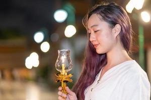 portrait young asian woman wearing traditional dress of Thailand holding candle for pray and meditation, Visakabucha day photo