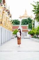 Young Asian buddhist woman wearing traditional dress of Thailand stand in church for relaxation and meditation, Sanctuary Ratchanatdaram bangkok. photo