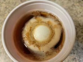 huevo disuelto en vaso de plástico de vinagre en el mostrador foto