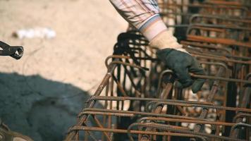 Worker working in construction. He connects the rebars with wire. Work safety. Construction material video