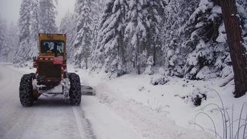 chasse-neige. la souffleuse à neige dégage la neige sur la route dans la forêt. video