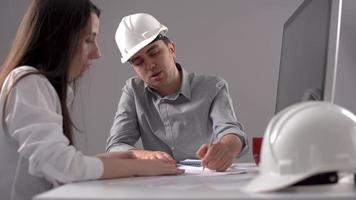 ingenieurs werken en handen schudden. ingenieurs die aan een project aan een bureau werken, sluiten een compromis en schudden elkaar de hand. video