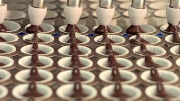 fábrica de produção de bolos e pastelaria. chocolate é derramado em pequenas caixas e colocado no forno. video