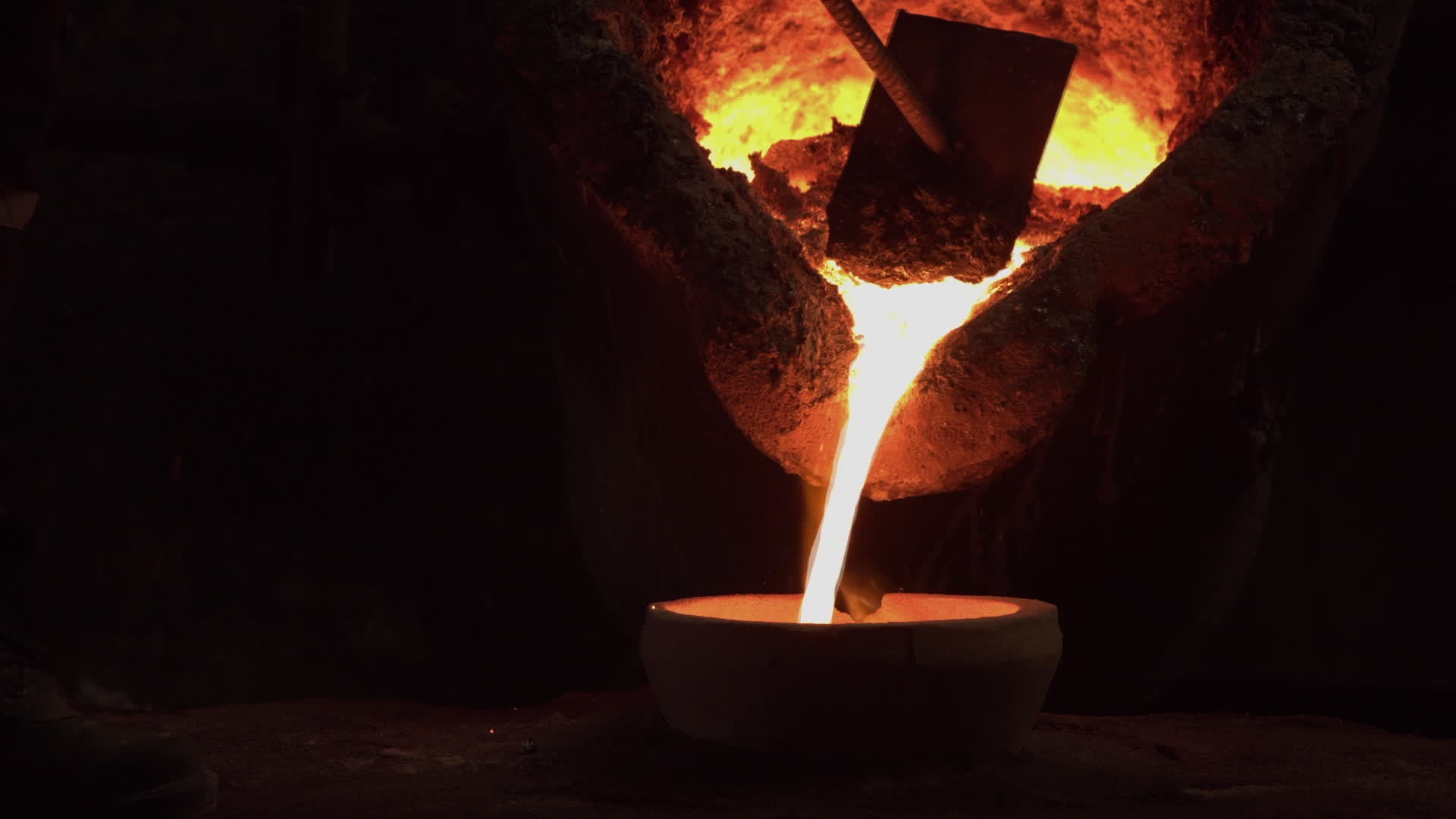 A furnace in which metal is melted. Sparks and smoke from the fire