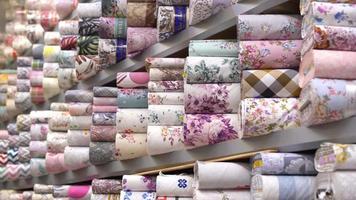 tipos de tecido, indústria têxtil. os tipos de tecidos alinhados nas prateleiras são utilizados na indústria têxtil. video
