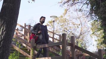 homme descendant les escaliers avec un sac à dos sur son épaule. monter les escaliers. escaliers de parc colorés. circulation piétonne intense. conditions pandémiques. précautions face au coronavirus. video