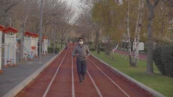 Running on the walking track in the park. Young man running in the park. Walking track. cold season. Sports equipment. video