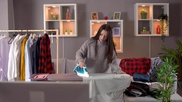 Young woman ironing happily at home.  The ironing woman is watching TV. video