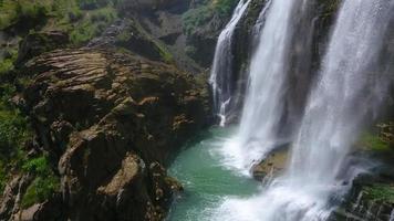 waterval tussen kliffen. luchtfoto van een waterval tussen ruige kliffen. video