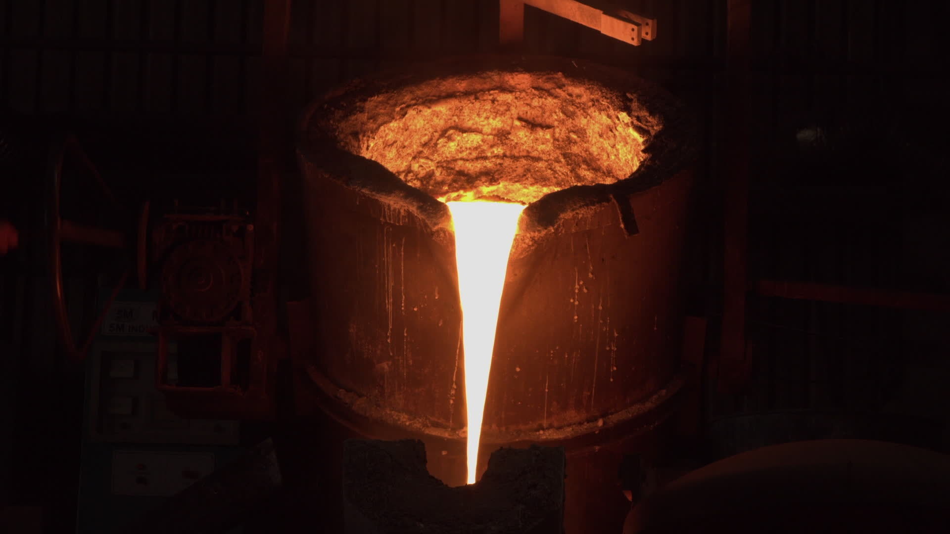 A furnace in which metal is melted. Sparks and smoke from the fire