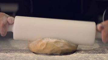 scena di gnocchi. scena di laminazione della pasta del maestro pasticcere. porta l'impasto a consistenza con un rullo rotante. video