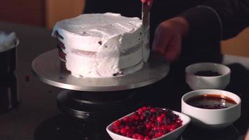 The pastry master rubs whipped cream around the edges of the cake. video