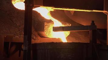 A furnace in which metal is melted. Sparks and smoke from the fire. metallurgical industry.Pouring bright hot liquid steel or metal from ladle in blast furnace foundry metallurgical factory.