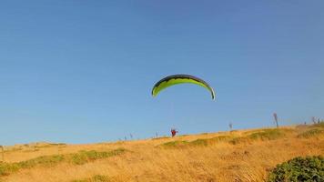 opstijgen door te paragliden. paraglider die opstijgt tegen een prachtig berg- en vlak landschap. video