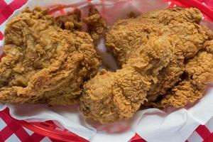 Fried chicken basket on red checkerboard tablecloth flat lay photo