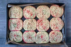 baking sheet of baked sugar cookies with red and green sprinkles flat lay photo