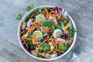 colorful bowl of fresh spring salad greens with broccoli and egg photo