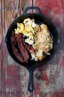 bacon strips, scrambled eggs, and hashbrowns in cast iron closeup flat lay