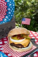 Fourth of July cheese burger with American flag on picnic table outdoors photo