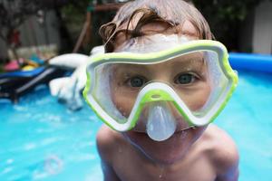 smiling young boy in swim goggles at pool photo