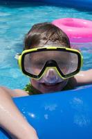 smiling young boy in swim goggles at pool photo