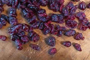 heap of healthy red dried cranberries on cutting board flat lay photo