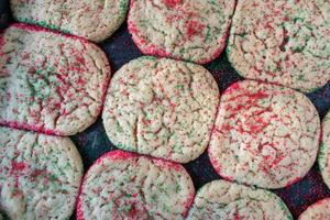 baking sheet of baked sugar cookies with red and green sprinkles flat lay photo