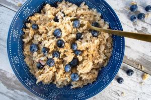 Bowl of oatmeal and blueberries on bright rustic setting flat lay photo