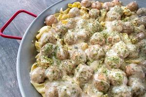 gran sartén de albóndigas suecas sobre fideos con salsa de crema y vista superior de perejil foto