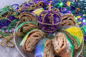 pastel de mardi gras en rodajas con un bebé rodeado de cuentas coloridas foto