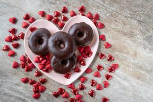 chocolate covered doughnuts on heart shaped plate surrounded by Valentine hearts photo