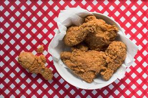 Fried chicken in white bowl on red and white checkered table flat lay photo